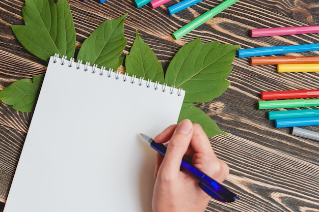 Foto mooi vrouwelijke hand schrijven in lege notitieblok op houten tafel