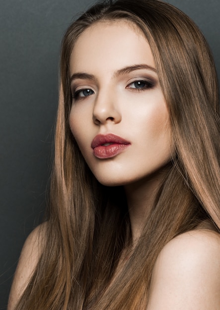 Mooi vrouwen modelportret met lang haar op donkere achtergrond. rode lippen