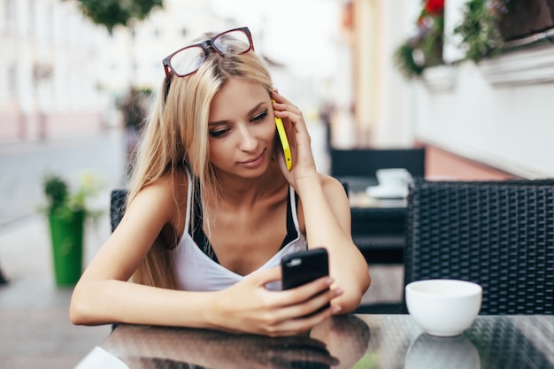 Mooi vrouwenblonde en sexy zitting op de straat in koffie, het drinken koffie en het babbelen en het spreken