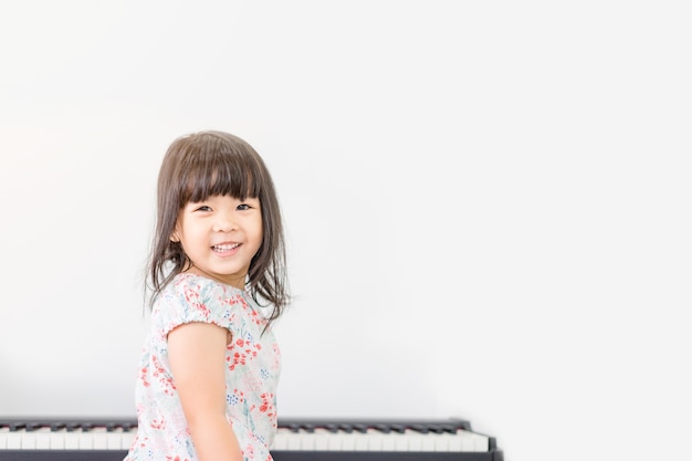 Mooi weinig Aziatische meisje het spelen piano in woonkamer.