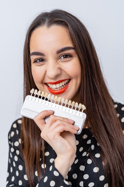 Mooi wijfje met tandenvoorbeelden. Model jonge vrouw met plastic nieuwe tanden.