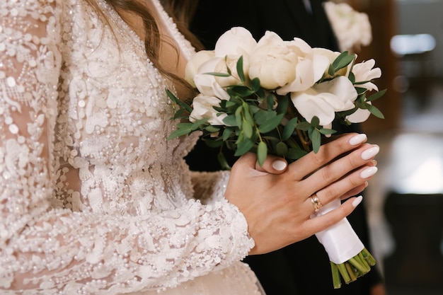 Mooi wit huwelijksboeket van pioenen in de handen van de bruid