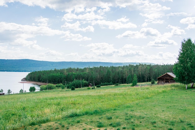 Mooi zomers Russisch landschap - een klein houten huis aan de rand van het bos aan de oever van de Siberische rivier