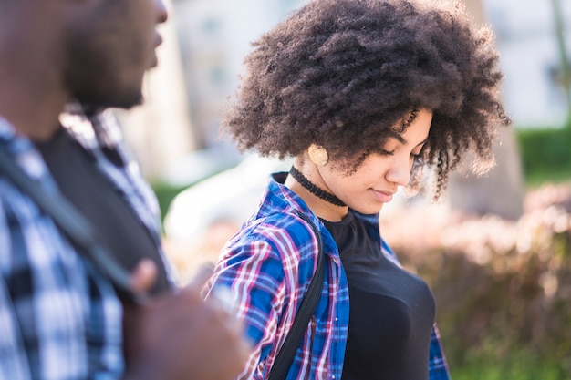 Mooi zwart krullend Afrikaans gemengd ras jong meisje dat buiten loopt met afro-vriendje