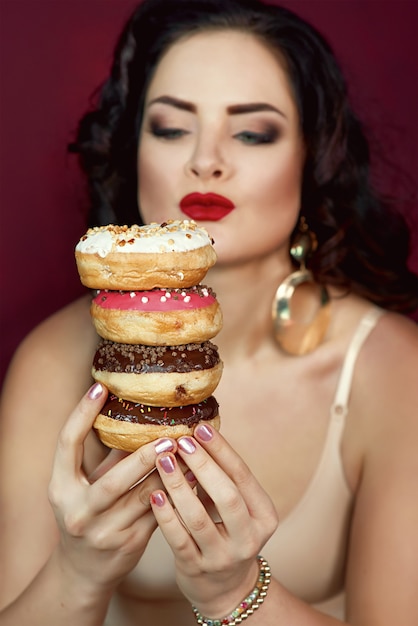 mooie aantrekkelijke donkerharige vrouw met kleurrijke smakelijke geglazuurde donuts