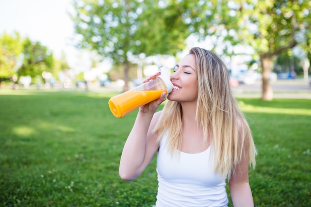 Mooie aantrekkelijke jonge vrouw die in openlucht gezond vers sinaasappelsap drinkt. Gezond levensstijlconcept.