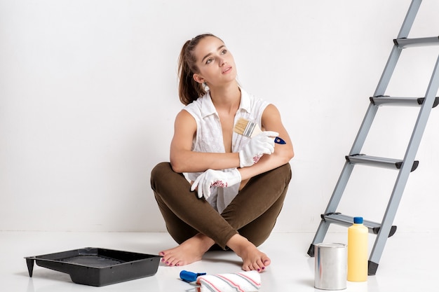 Mooie aantrekkelijke vrouw die een muur in haar huis schildert