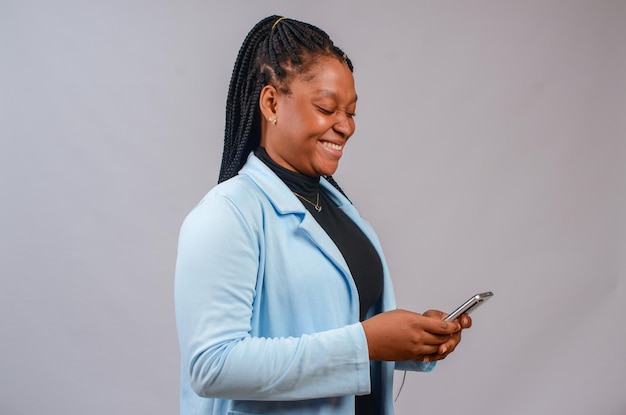 Mooie Afrikaanse dame geïsoleerd op witte achtergrond glimlachend terwijl ze haar telefoon bedient