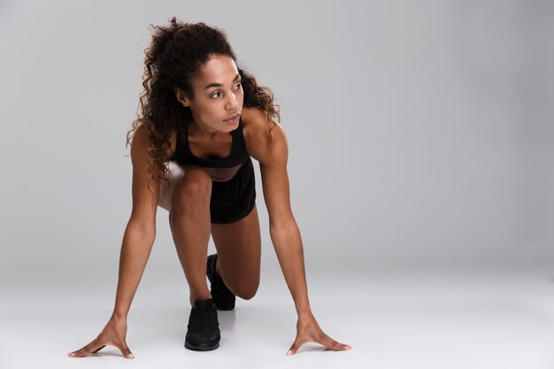 Mooie Afrikaanse sportvrouw klaar om te beginnen met geïsoleerd over grijze achtergrond