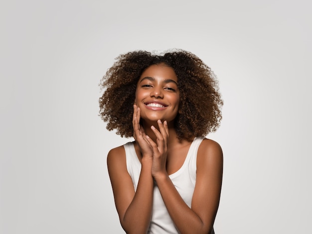 Mooie Afrikaanse vrouw wit t-shirt portret afro kapsel wat betreft haar gezicht Kleur achtergrond grijs