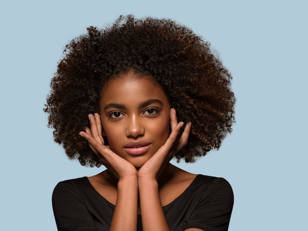 Mooie Afrikaanse vrouw zwart t-shirt portret afro kapsel wat betreft haar gezicht Kleur achtergrond blauw