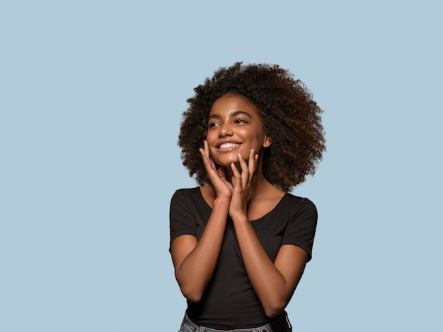 Mooie Afrikaanse vrouw zwart t-shirt portret afro kapsel wat betreft haar gezicht Kleur achtergrond blauw