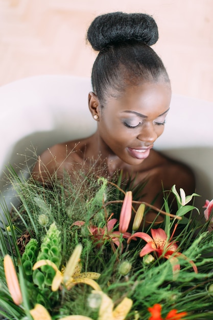 Mooie Afro-Amerikaanse bruid in versierd bad. Mooie Afro-Amerikaanse vrouw in bad met boeket