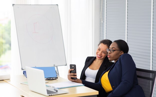 Mooie Afro-Amerikaanse en Spaanse zakenvrouw werken op laptopcomputer samen op moderne kantoor aan huis.