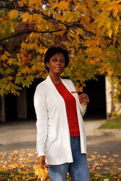 Mooie Afro-Amerikaanse vrouw die in een herfsttuin loopt