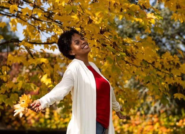 Mooie Afro-Amerikaanse vrouw die in een herfsttuin loopt