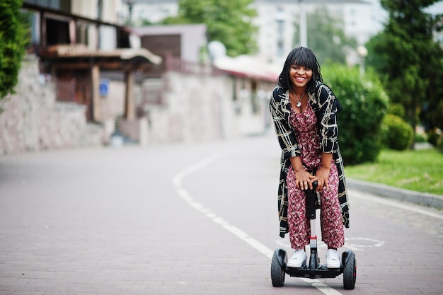 Mooie afro-amerikaanse vrouw die segway of hoverboard gebruikt Zwart meisje op een zelfbalancerende elektrische scooter met twee wielen