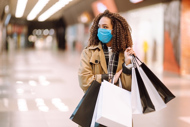 Mooie Afro-Amerikaanse vrouw met beschermend masker na het winkelen in de buurt van de winkel