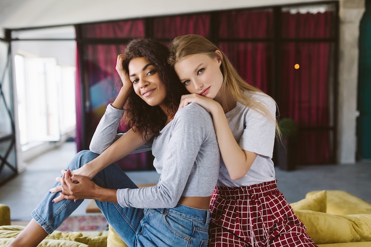 Foto mooie afro-amerikaanse vrouw met donker krullend haar en mooie vrouw met blond haar dromerig op elkaar leunend terwijl ze samen tijd doorbrengen thuis