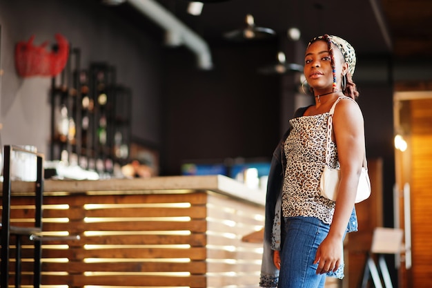 Mooie afro-amerikaanse vrouw met dreadlocks in luipaardoutfit in café Mooi cool, modieus zwart jong meisje binnen