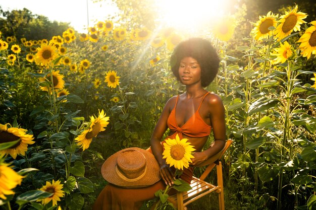 Mooie Afro-Amerikaanse vrouw met krullend haar in afrostijl in een zonnebloemenveld