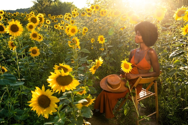 Mooie Afro-Amerikaanse vrouw met krullend haar in afrostijl in een zonnebloemenveld