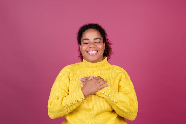 Mooie afro-amerikaanse vrouw op roze muur gelukkig lachende handen op borst hou van jezelf concept, zelfzorg