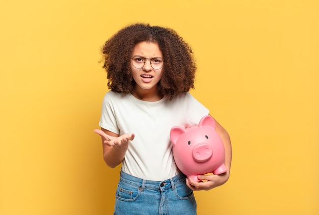 Mooie afro tiener die geschokt kijkt, met de hand en tussen de vingers gluurt. spaarconcept