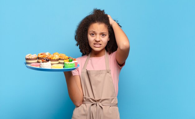 Mooie afro-tiener die zich gestrest, bezorgd, angstig of bang voelt, met de handen op het hoofd, in paniek raakt bij vergissing. humoristisch bakkersconcept