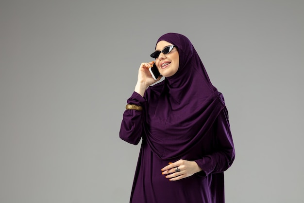 Mooie arabische vrouw poseren in stijlvolle hijab geïsoleerd op studio achtergrond. mode concept