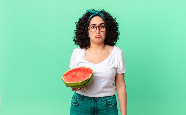 Mooie arabische vrouw voelt zich verdrietig en zeurt met een ongelukkige blik en huilt en houdt een watermeloen vast. zomer concept