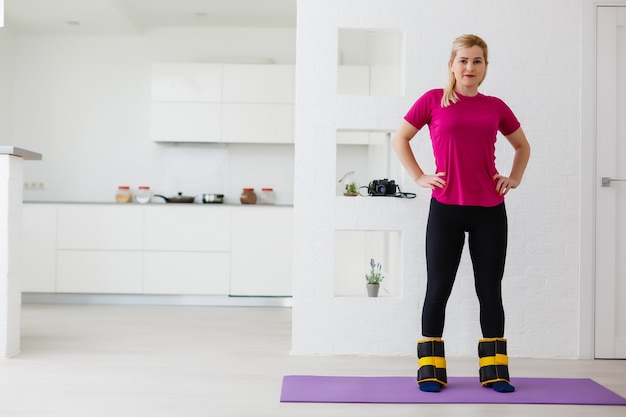 Mooie atletische jonge moderne vrouw gaat sporten met gewichten thuis