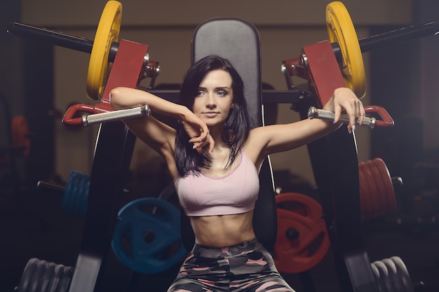 Mooie atletische jonge vrouw die in gymnastiek uitwerkt