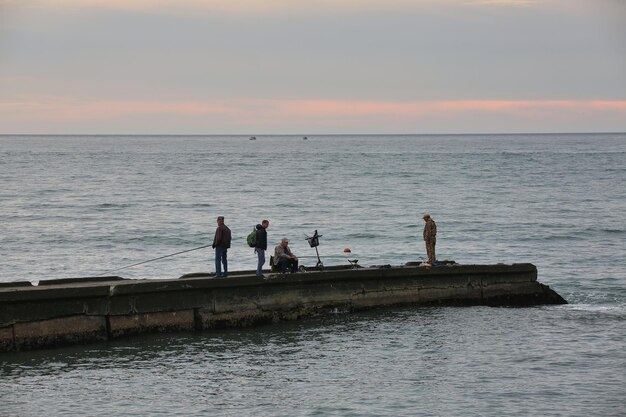 Mooie avond aan zee en vissers die vissen op de pier.