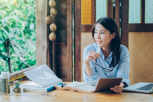 Mooie Aziatische bedrijfsvrouw die met laptop, telefoon, en tablet werkt