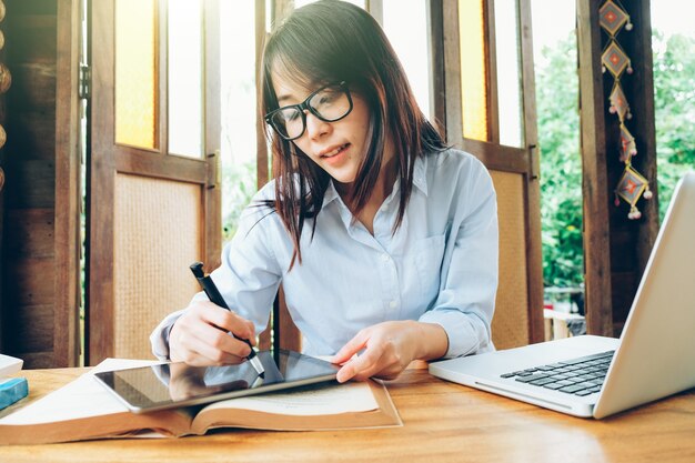 Mooie Aziatische bedrijfsvrouw die met laptop, telefoon, en tablet werkt