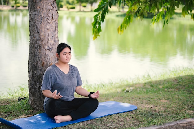 Mooie Aziatische dikke vrouw speelt yoga in het parkMoet een slank lichaam hebben