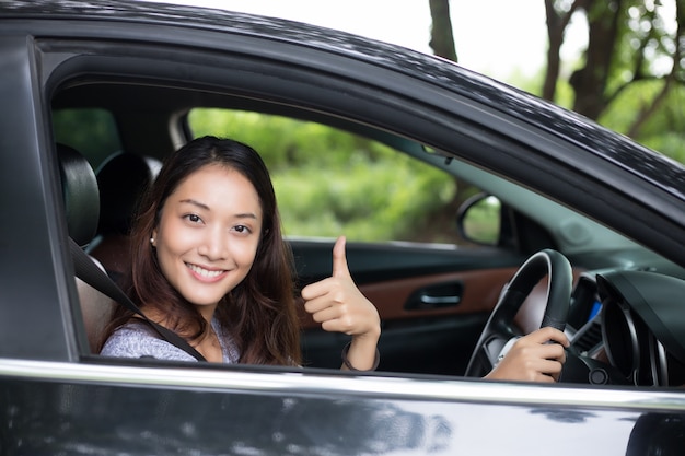 Mooie Aziatische en vrouw die glimlacht geniet van. Drijvend een auto op weg voor reis