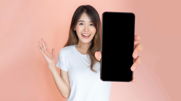 Mooie Aziatische jonge vrouw met grote slimme telefoon met leeg scherm wit scherm lege kopie ruimte voor reclamebanner geïsoleerd op roze achtergrond Mock Up Image