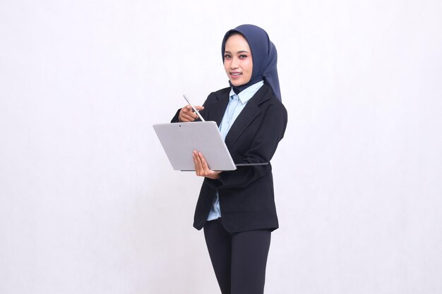 Mooie Aziatische kantoorvrouw met een hijab staat glimlachend naar de camera te wijzen en een t te bedienen