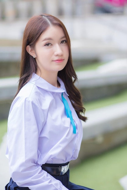 Mooie Aziatische middelbare school student meisje in het schooluniform met beugels op haar tanden zitten.