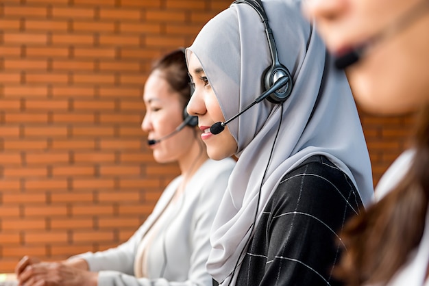 Mooie aziatische moslimvrouw die in call centre met haar team werkt