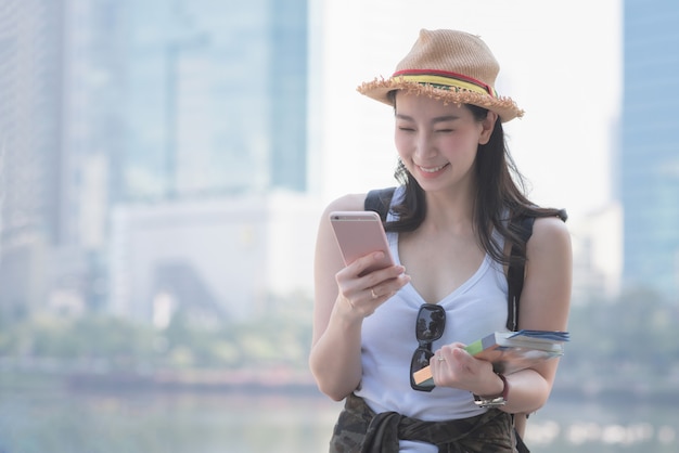 Mooie Aziatische solo toeristische vrouw glimlachend en kijken naar mobiele telefoon