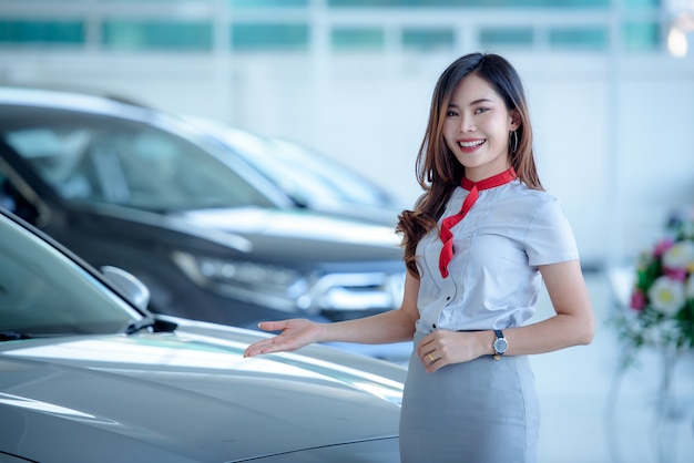 Mooie Aziatische verkopers verkopen graag nieuwe auto's in de showroom en laten klanten auto's kopen bij autodealers.