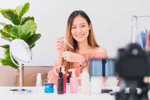 Mooie Aziatische vrouw blogger laat zien hoe ze make-up en cosmetica gebruiken en thuis vlog-video opnemen.