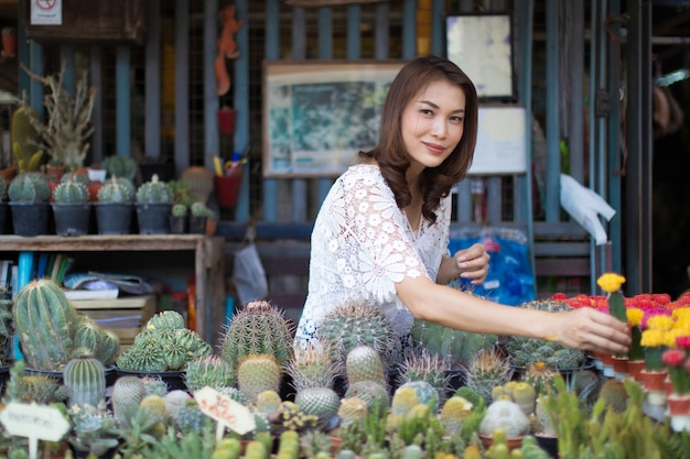 Mooie aziatische vrouw die cactus in bloemenwinkel selecteert, levensstijl van moderne huisvrouw.