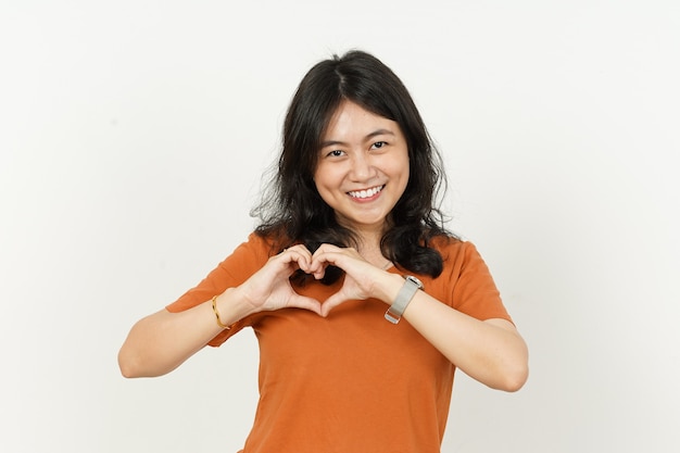 Mooie Aziatische vrouw die een oranje T-shirt draagt, maakt en toont een liefdesharthandteken