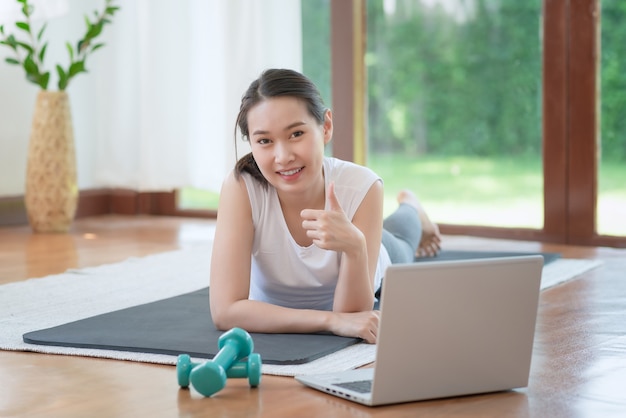 Mooie aziatische vrouw die fit blijft door thuis te trainen voor een gezonde trendlevensstijl