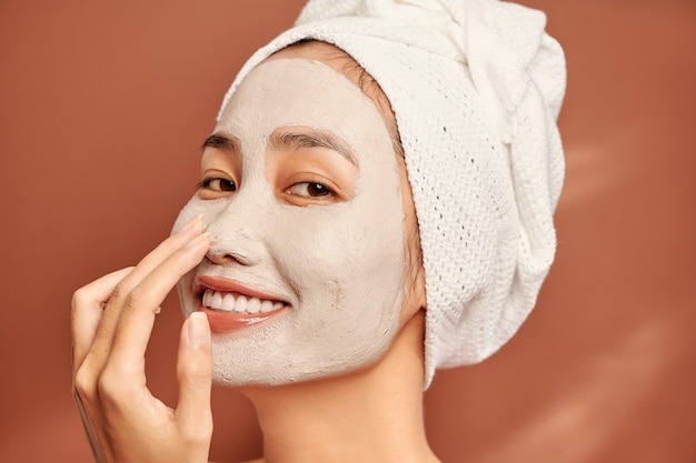 Mooie Aziatische vrouw die gezichtsmasker op haar gezicht toepast. Huidverzorging en -behandeling, spa, natuurlijke schoonheid en cosmetologie concept.