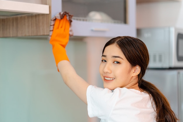 Mooie aziatische vrouw die keukenkasten schoonmaakt